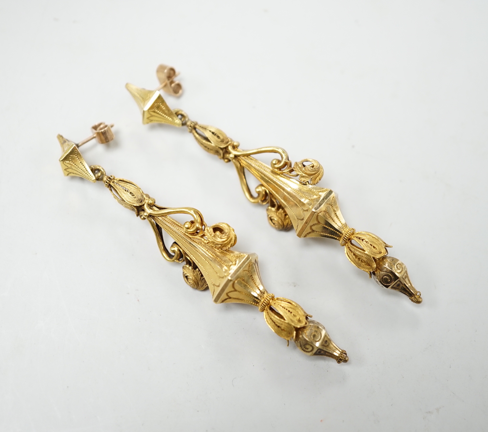 A pair of early 20th century yellow metal drop earrings, with scroll decoration, (later fittings?), 81mm, gross weight 10 grams.